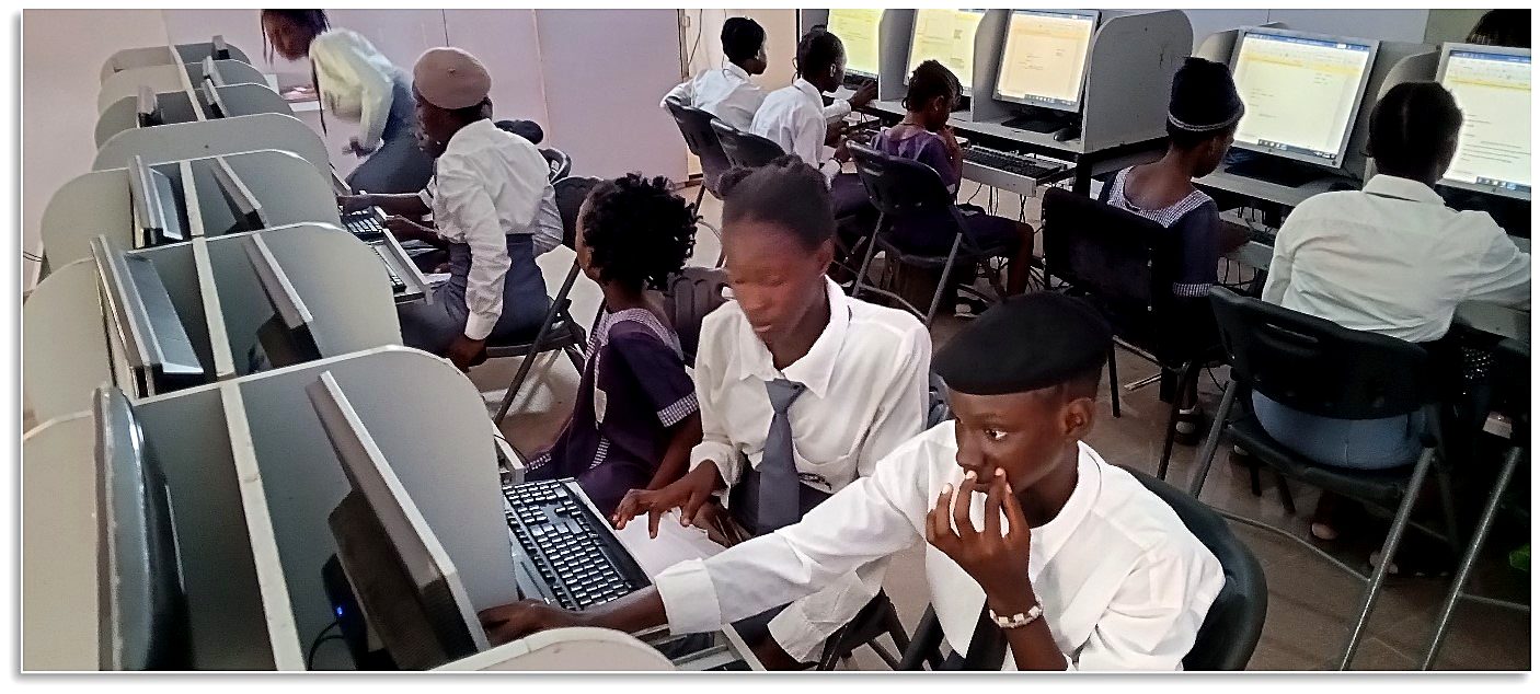 Younger students seated at a row of computers in an ICT lab